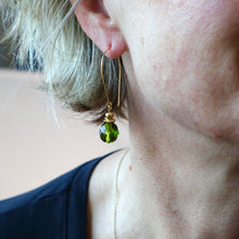 Load image into Gallery viewer, Close-up of a person wearing a green bead earring with gold detailing.