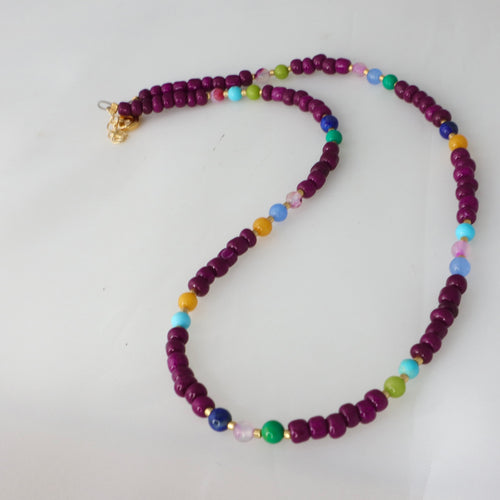 Necklace with purple beads and colorful accents on a white background
