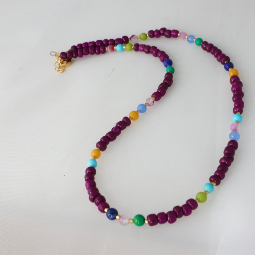 Necklace with purple beads and colorful accents on a white background