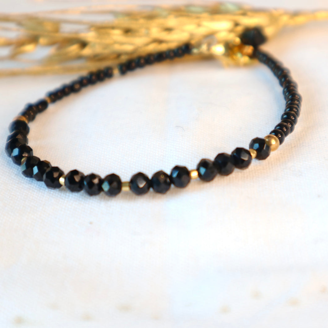 Black beaded bracelet on a white surface with a blurred background