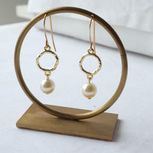 Load image into Gallery viewer, Gold earrings with pearls on a wooden stand against a white background
