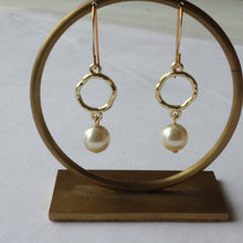 Load image into Gallery viewer, Gold earrings with pearl drops on a wooden stand against a white background