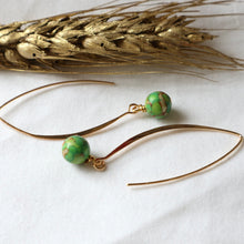 Load image into Gallery viewer, Gold earrings with green beads on a white background with wheat.