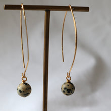 Load image into Gallery viewer, Gold earrings with spherical stones on a stand against a neutral background