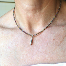 Load image into Gallery viewer, A close-up of a person's neck and upper chest wearing a delicate beaded necklace with a small silver teardrop pendant.