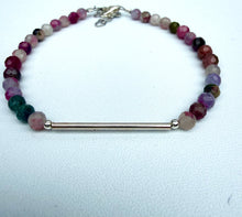 Load image into Gallery viewer, A beaded bracelet featuring faceted round gemstone beads in shades of pink, purple, green, and red, with a central polished silver bar and silver clasp, displayed on a textured white surface.