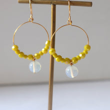 Load image into Gallery viewer, Gold hoop earrings with yellow beads and moonstone drops on a neutral background.