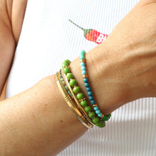 Load image into Gallery viewer, Close-up of a wrist wearing multiple bracelets with green and turquoise beads on a white background.
